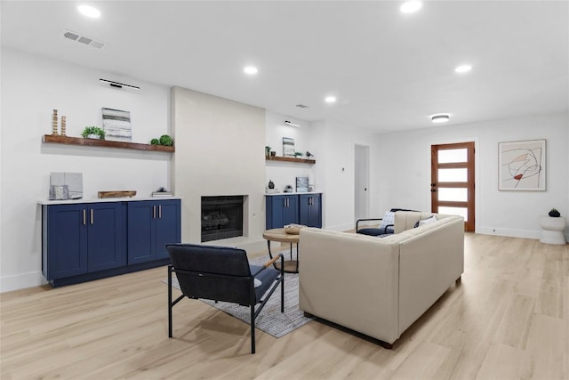 living room featuring a large fireplace and light hardwood / wood-style floors