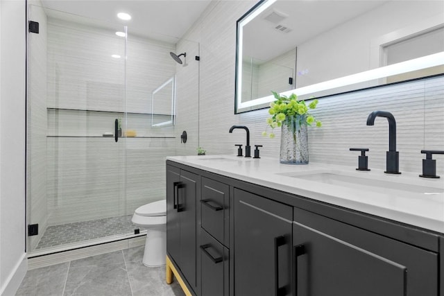 bathroom with a shower with door, vanity, tile walls, and toilet