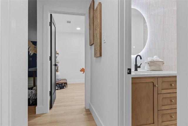 corridor with sink and light hardwood / wood-style flooring