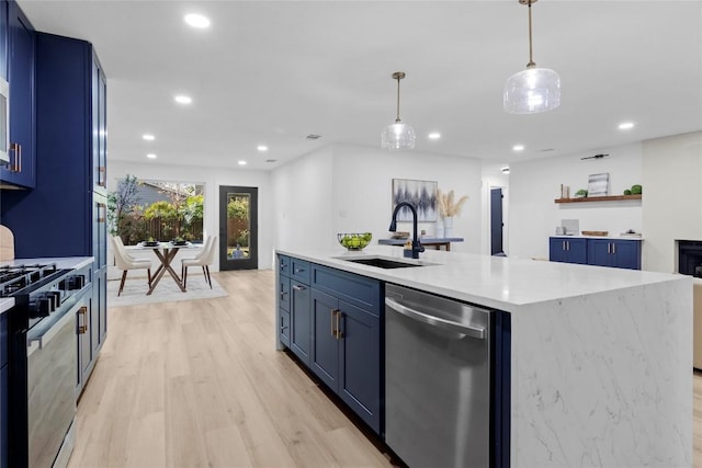 kitchen with blue cabinetry, sink, an island with sink, decorative light fixtures, and appliances with stainless steel finishes