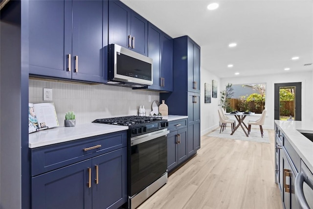 kitchen with decorative backsplash, stainless steel gas range oven, light hardwood / wood-style floors, and blue cabinets