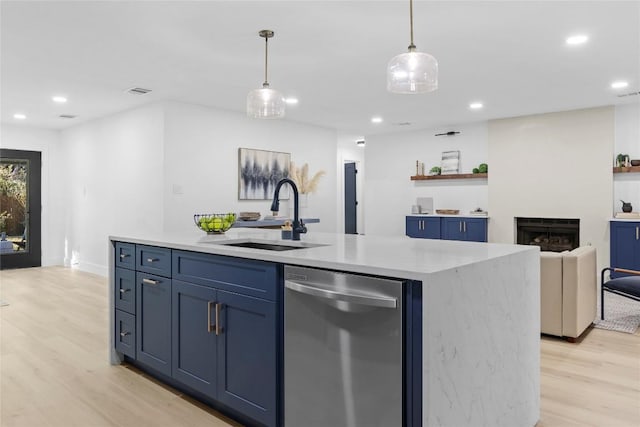 kitchen featuring blue cabinetry, sink, light hardwood / wood-style flooring, stainless steel dishwasher, and a center island with sink