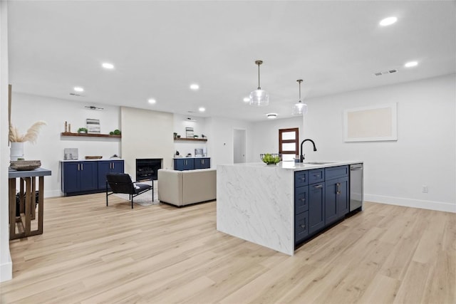 kitchen featuring dishwasher, blue cabinets, a fireplace, and hanging light fixtures