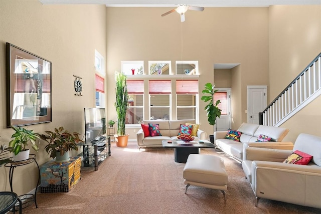 living room with ceiling fan, a towering ceiling, and carpet