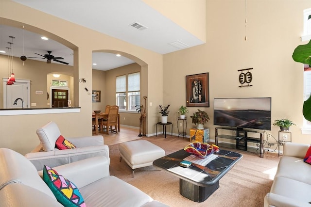 carpeted living room with ceiling fan and sink