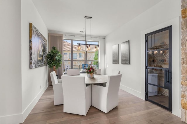 dining room with hardwood / wood-style floors and an inviting chandelier