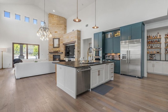 kitchen featuring blue cabinetry, sink, hanging light fixtures, stainless steel appliances, and light hardwood / wood-style floors