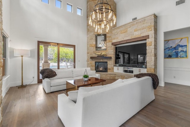 living room featuring hardwood / wood-style flooring, a notable chandelier, a fireplace, and a high ceiling