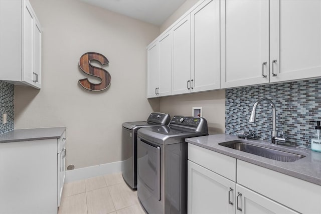 laundry room featuring a sink, washing machine and dryer, light tile patterned flooring, baseboards, and cabinet space