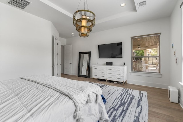 bedroom featuring a raised ceiling, a chandelier, and dark hardwood / wood-style floors