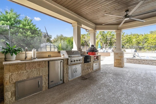 view of patio / terrace featuring a ceiling fan, a sink, a grill, an outdoor kitchen, and fence
