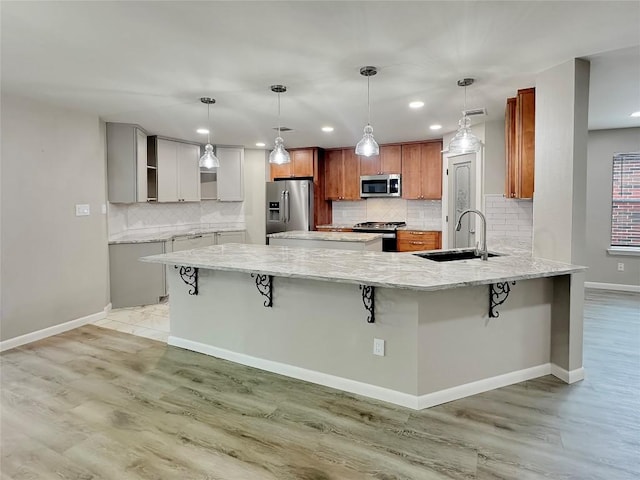 kitchen with sink, a kitchen breakfast bar, decorative light fixtures, white cabinets, and appliances with stainless steel finishes