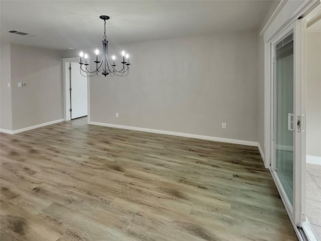 unfurnished dining area with hardwood / wood-style floors and an inviting chandelier