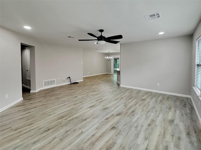 unfurnished living room featuring ceiling fan with notable chandelier and light hardwood / wood-style flooring