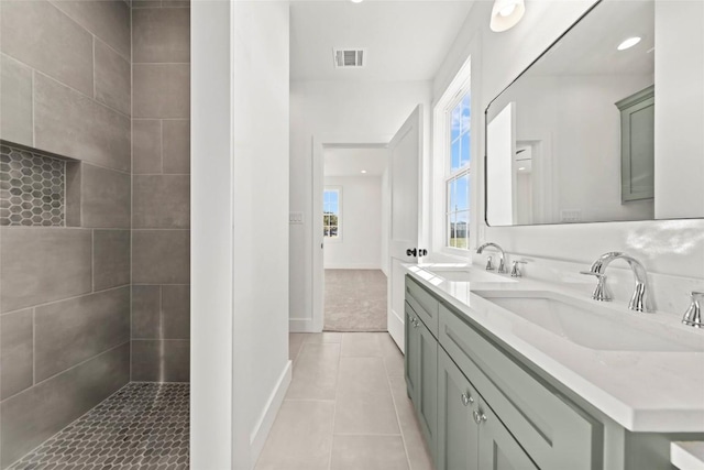 bathroom with tile patterned floors, vanity, and a tile shower