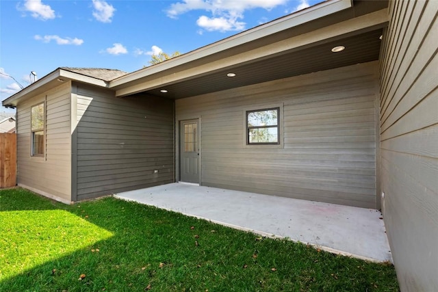 view of exterior entry with a patio area and a lawn