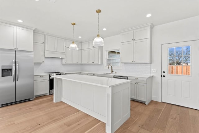 kitchen with sink, a center island, hanging light fixtures, white cabinets, and appliances with stainless steel finishes