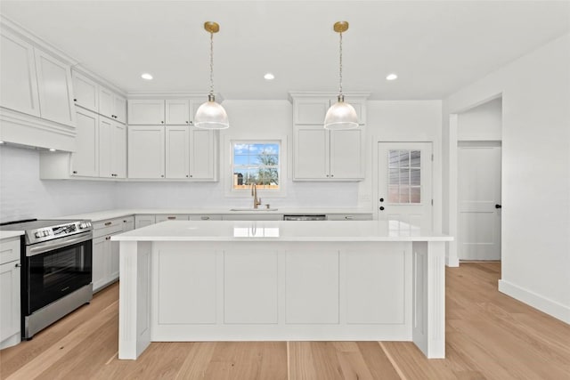 kitchen featuring white cabinetry, a kitchen island, hanging light fixtures, and stainless steel electric range