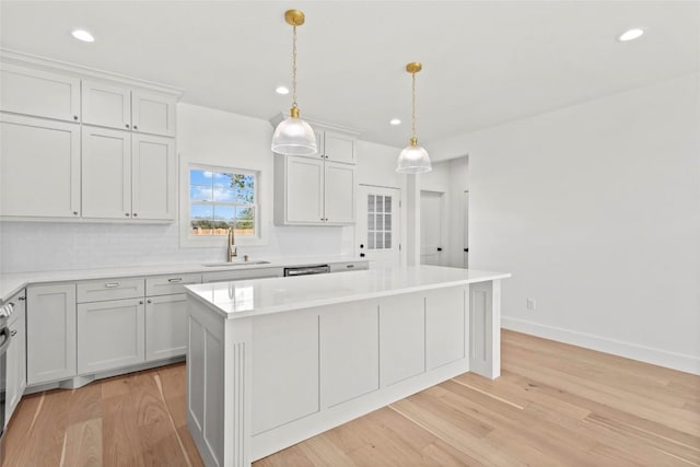 kitchen with a center island, sink, pendant lighting, decorative backsplash, and light wood-type flooring