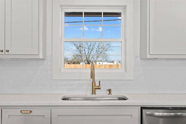 room details with stainless steel dishwasher, white cabinets, and sink