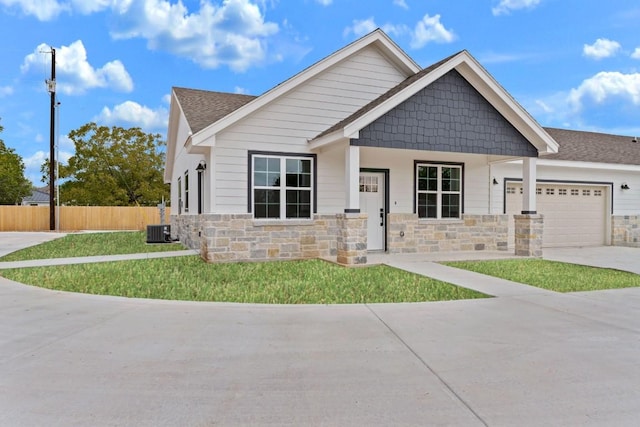 craftsman-style house with a front yard, central AC unit, and a garage