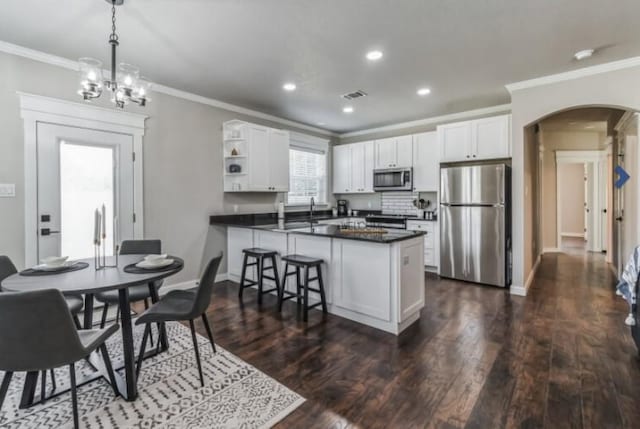 kitchen featuring kitchen peninsula, dark hardwood / wood-style flooring, stainless steel appliances, decorative light fixtures, and white cabinets