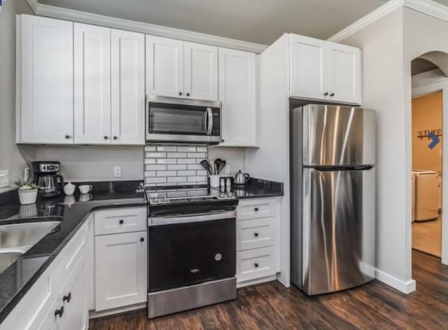 kitchen featuring dark hardwood / wood-style floors, crown molding, washer / dryer, white cabinets, and appliances with stainless steel finishes