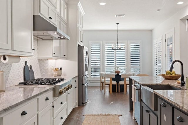 kitchen with light stone counters, white cabinets, and pendant lighting