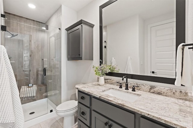 bathroom featuring tile patterned floors, vanity, a shower with shower door, and toilet