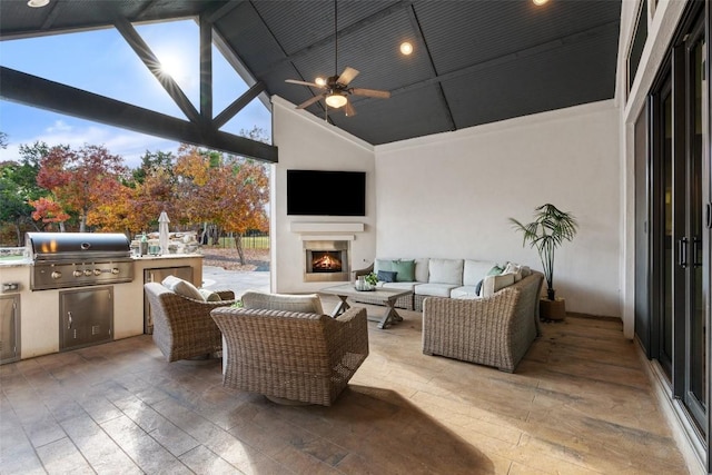 view of patio / terrace with an outdoor living space with a fireplace, ceiling fan, area for grilling, and exterior kitchen