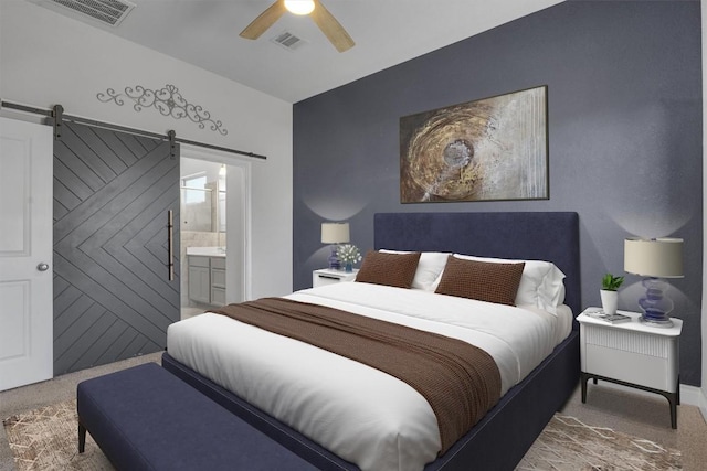 carpeted bedroom featuring a barn door, ceiling fan, and ensuite bathroom