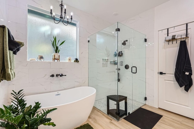 bathroom with wood-type flooring, separate shower and tub, tile walls, and a notable chandelier