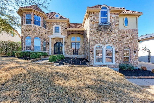 mediterranean / spanish house featuring a front lawn and french doors