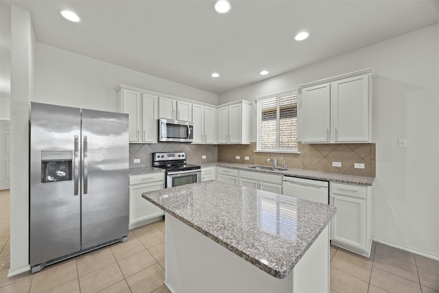 kitchen with white cabinets, decorative backsplash, stainless steel appliances, and light stone counters