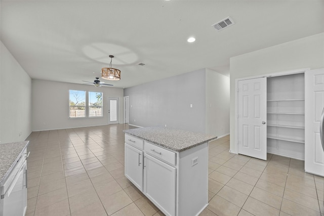 kitchen with ceiling fan, decorative light fixtures, light tile patterned flooring, light stone counters, and white cabinetry