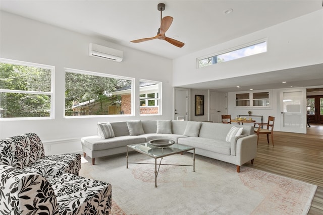 living room with ceiling fan, a wall mounted air conditioner, and hardwood / wood-style flooring