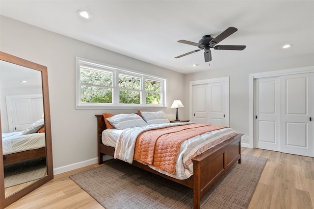 bedroom featuring light wood-type flooring, two closets, and ceiling fan