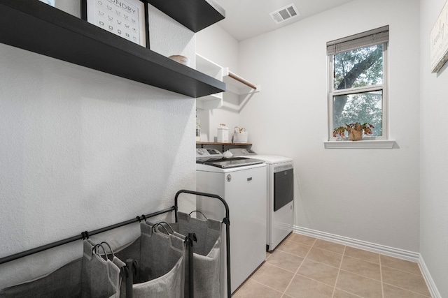 laundry room featuring washing machine and dryer and light tile patterned flooring