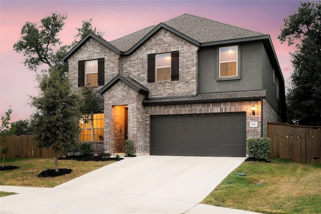 traditional-style house featuring brick siding, an attached garage, a front lawn, and fence