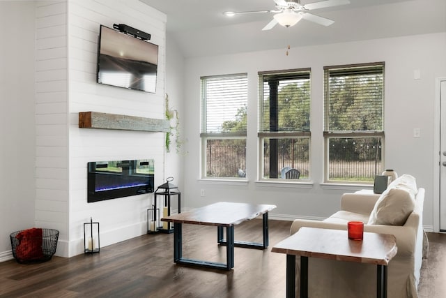 interior space featuring a large fireplace, ceiling fan, baseboards, lofted ceiling, and dark wood-style flooring