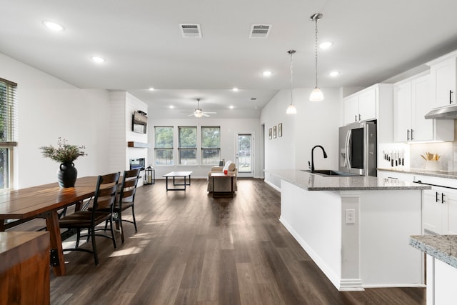 kitchen featuring decorative light fixtures, white cabinetry, light stone counters, ceiling fan, and stainless steel refrigerator