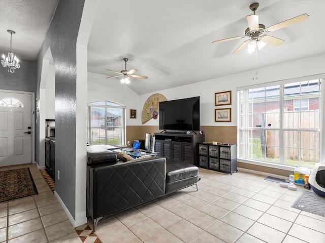 living room with light tile patterned floors, ceiling fan with notable chandelier, and vaulted ceiling