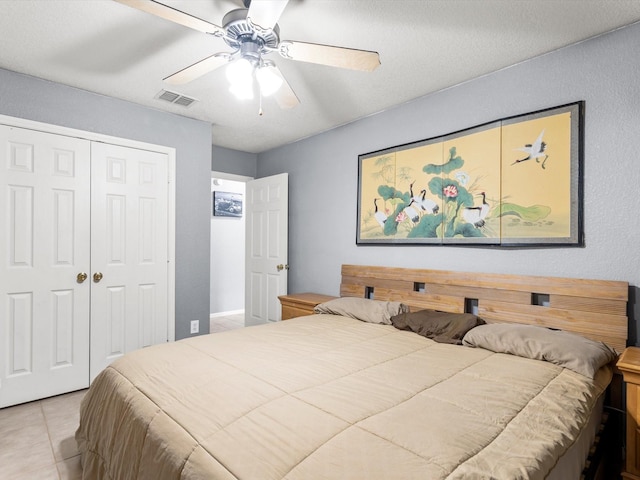 bedroom featuring light tile patterned floors, a textured ceiling, a closet, and ceiling fan