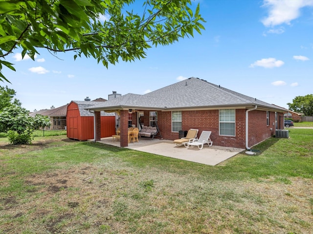 back of property with a storage unit, central AC unit, a patio area, and a lawn