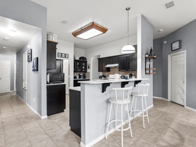 kitchen with a breakfast bar area, kitchen peninsula, tasteful backsplash, and light tile patterned floors