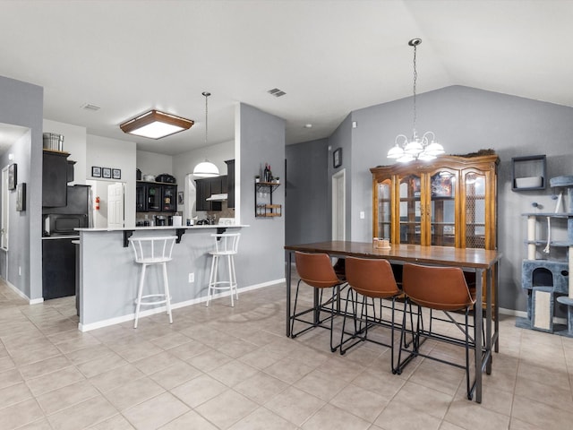 kitchen featuring lofted ceiling, light tile patterned floors, a kitchen bar, kitchen peninsula, and a chandelier