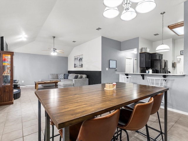 tiled dining space featuring ceiling fan with notable chandelier and lofted ceiling