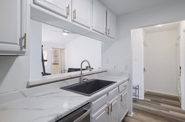 kitchen with dishwasher, sink, white cabinetry, light stone counters, and wood-type flooring