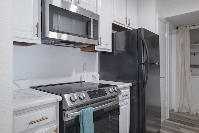 kitchen with white cabinets, light wood-type flooring, and appliances with stainless steel finishes