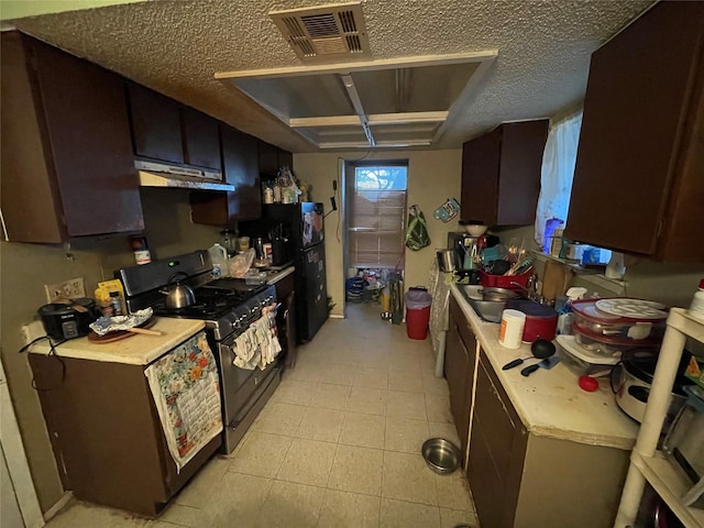 kitchen featuring a textured ceiling, gas stove, dark brown cabinetry, and sink